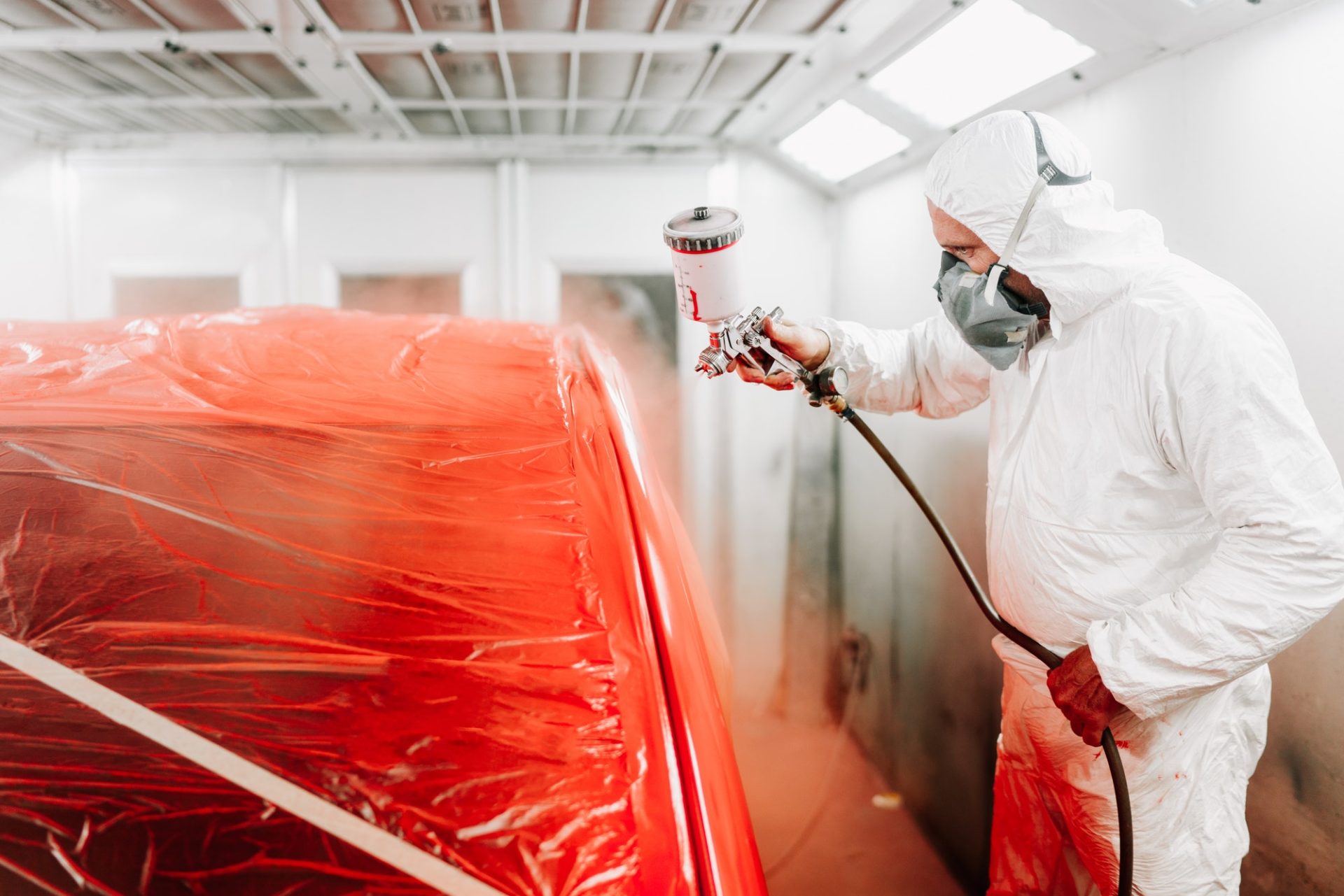 automotive-industry-engineer-using-spray-gun-and-painting-a-red-car-e1635819622219.jpg